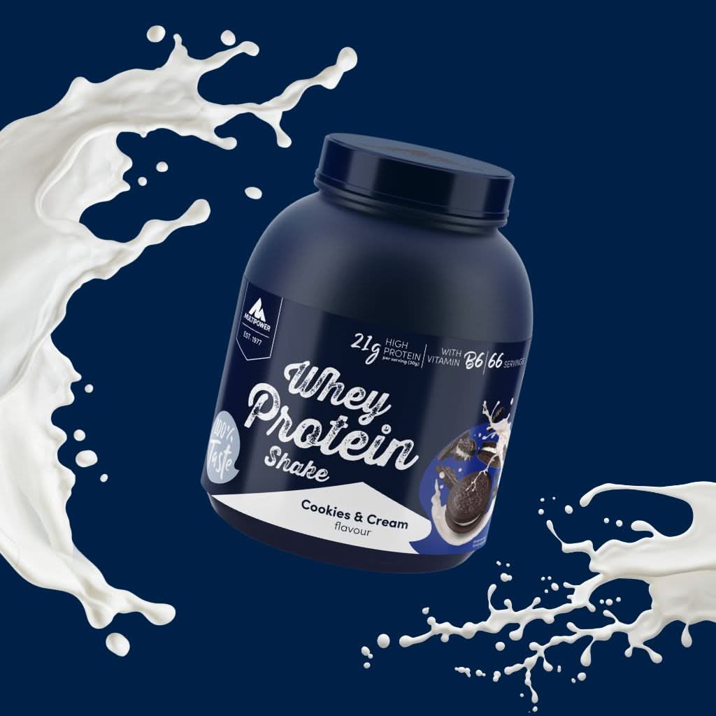 Große 2 kg Dose Whey-Protein in der Sorte Cookies & Cream vor einem intensiven dunkelblauen Hintergrund, stilvoll in Szene gesetzt mit dynamisch gespritzten Milch- und Cremespritzern – vermittelt Frische und Genuss zugleich