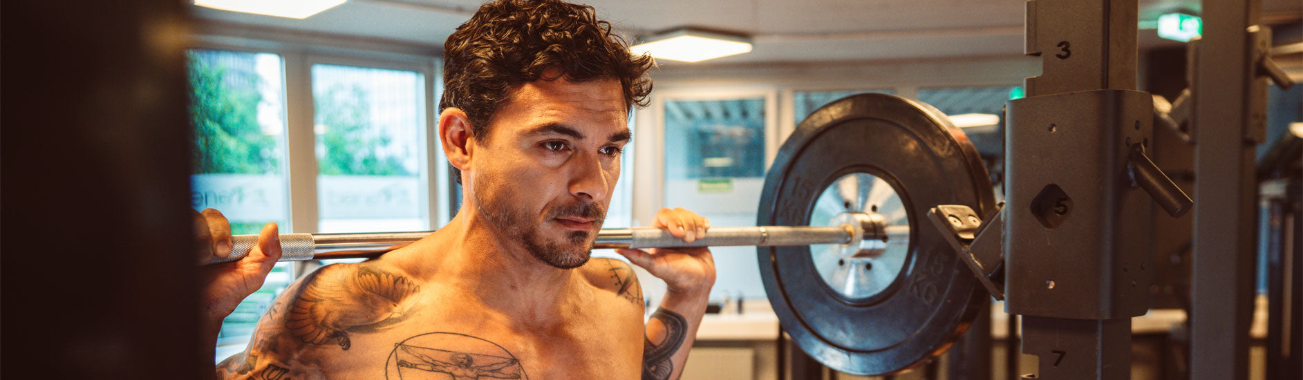 Multipower Model trainiert im Fitnessstudio mit Langhantel