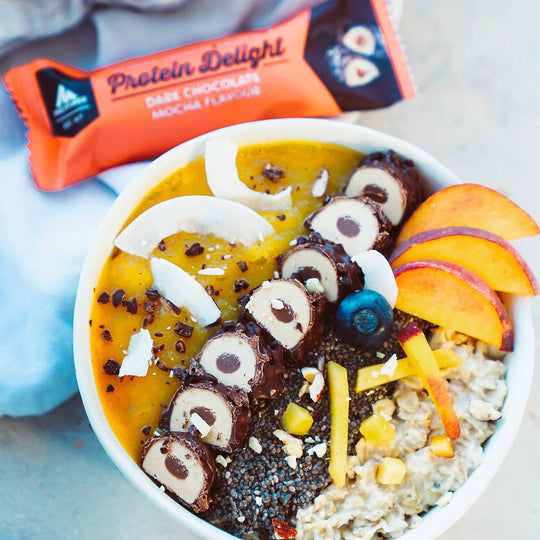 Protein Delight Riegel von Multipower neben Müsli-Bowl mit Früchten, Riegelstücke als Topping in der Schale.